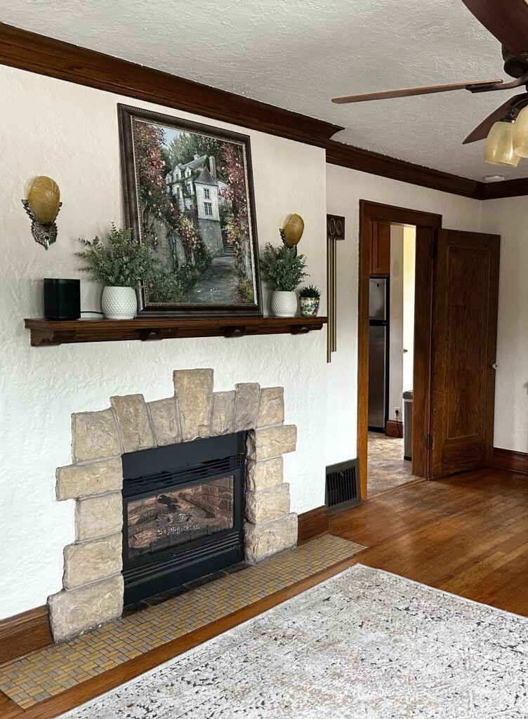 Stone fireplace in old home, rustic style, oak mantel, wood floor, dark wood stained trim, Benjamin MOore Maritime White beige paint color on walls