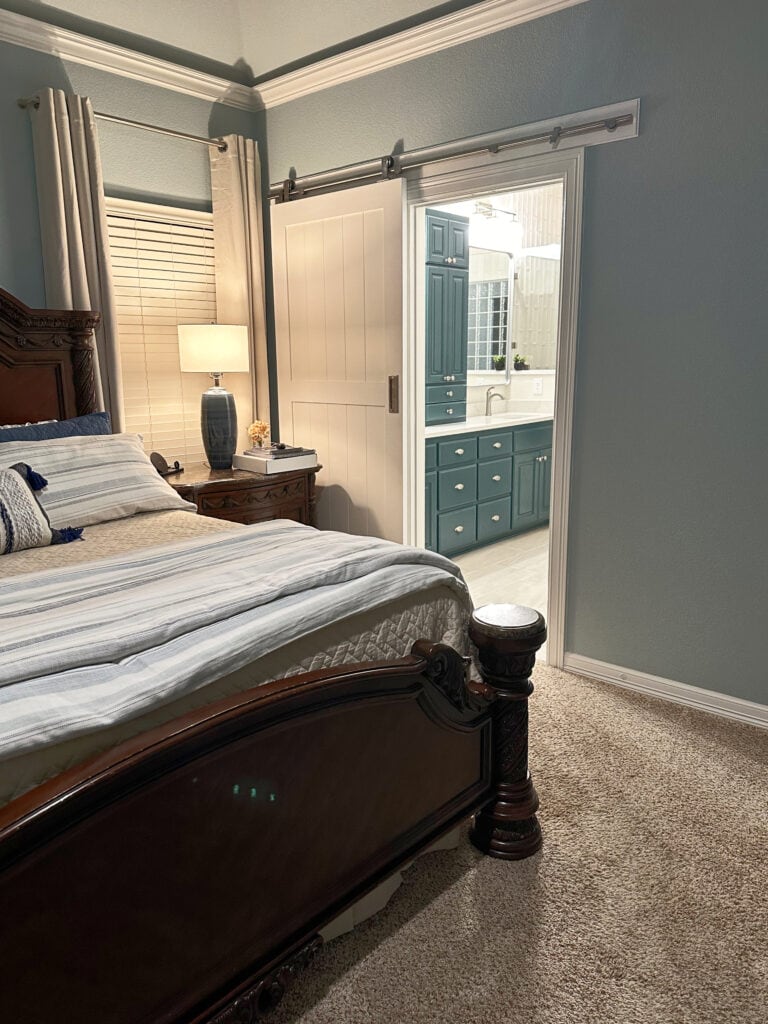 Bedroom painted Sherwin Williams RAin, blue paint color, beige carpet, bathroom with Riverway wood vanity