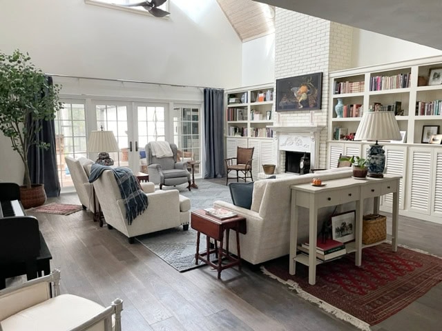 Living room with a high, cathedral or vaulted ceiling, built ins, Sherwin Williams Antique White, wood floor.