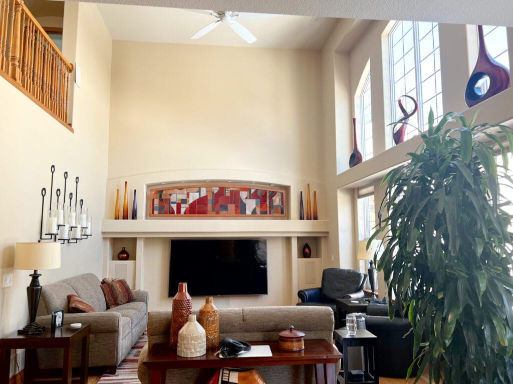 Living room with a high vaulted ceiling, Benjamin Moore Alpaca, warm beige paint color on walls, alcove niche above TV.