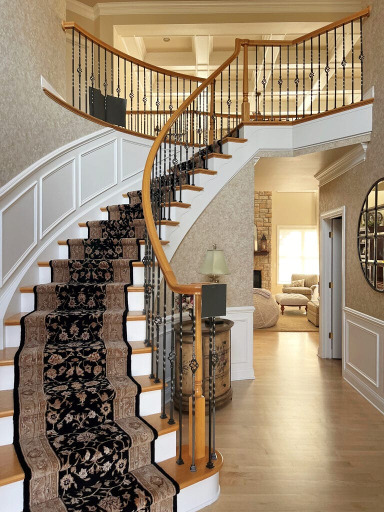 2000 staircase with oak wood hand railing and treads, white risers, wainscoting, sponge paint look beige walls, curved railing, maple floor