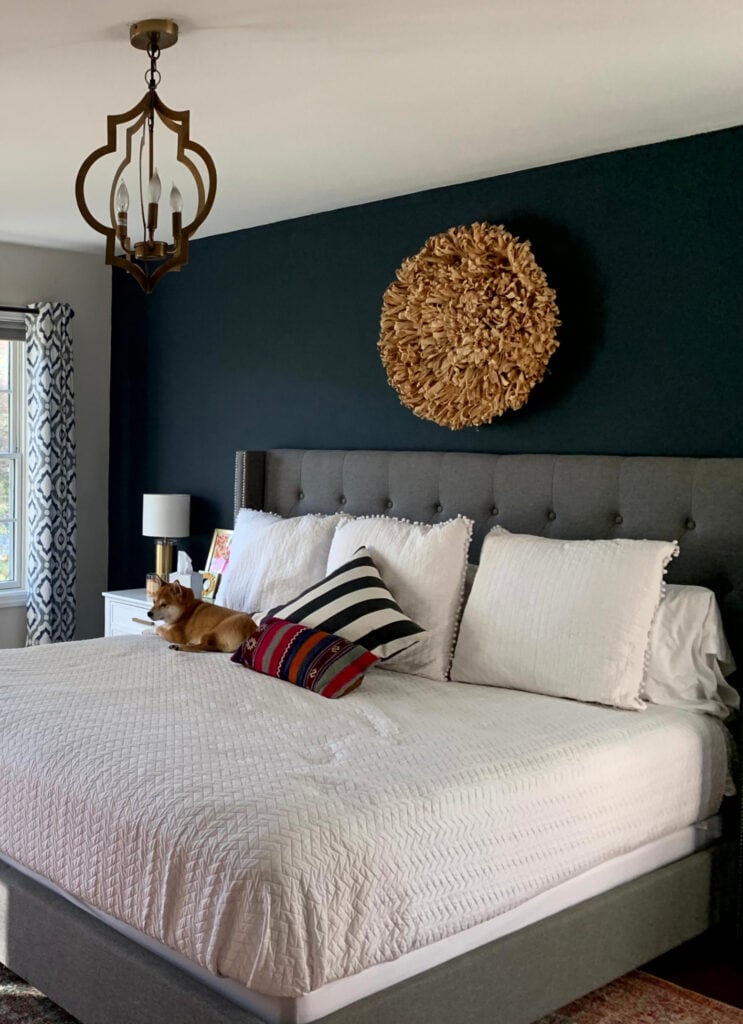 Benjamin Moore Hale Navy accent wall, Silver Satin, primary bedroom, wood floor, gray upholstered bed. Off white warm gray wall color. Kylie M blog