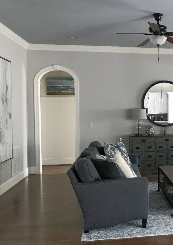 Benjamin Moore Silver Gray, blue-gray paint color on ceiling in living room with Collingwood on walls, dark wood floor, dark furniture, transitional home decor, crown molding (1)
