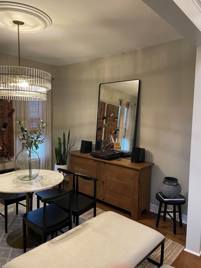 Dining room in Revere Pewter with wood buffet, moody, round marble table and black chairs.