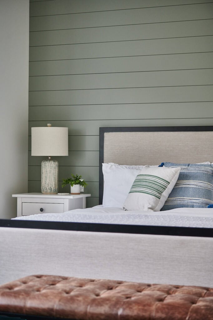 Sherwin Williams Evergreen fog, best shade of green paint color on shiplap accent wall in bedroom with upholstered headboard. Kylie M, online paint color expert