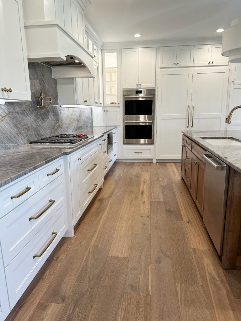 Stainless steel appliances, Sherwin Williams Pure White painted cabinets, wood oak floor, countersplash, island wood, gray brown quartzite quartz countertops, wood island, wood floor, Kylie M Interiors International paint color expert. 