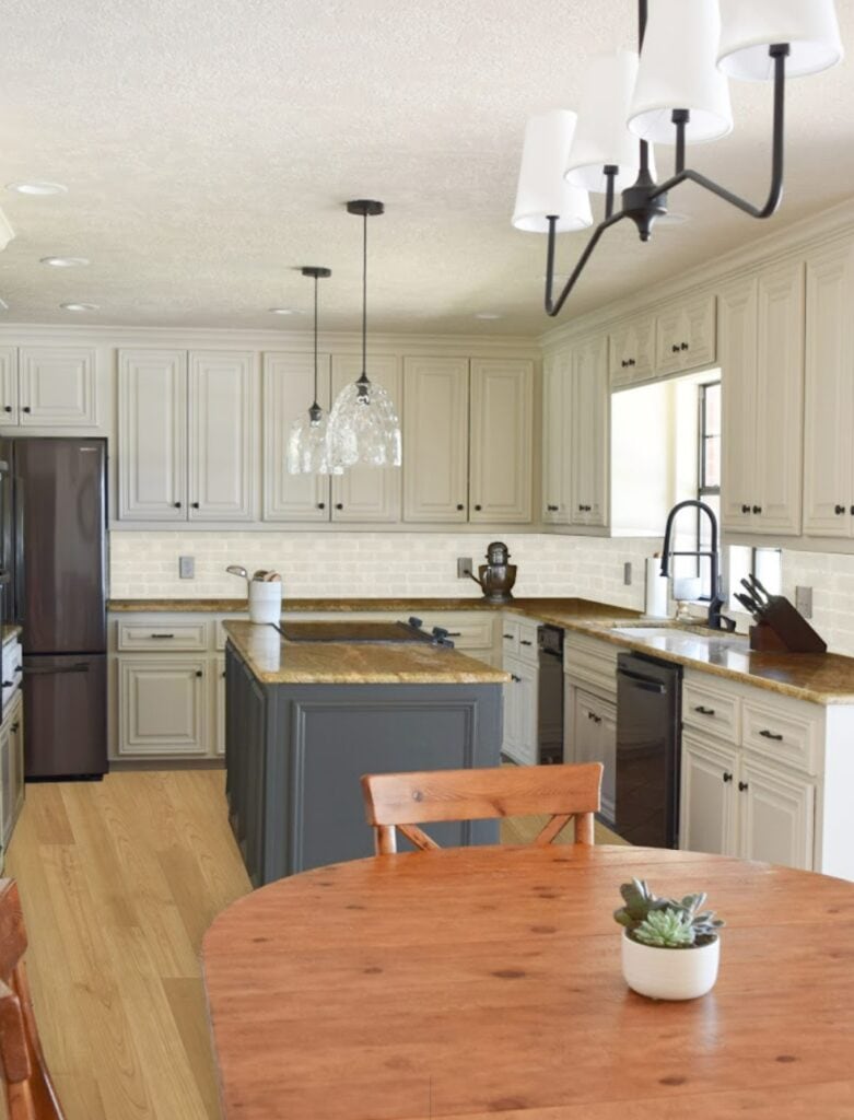 kitchen with painted cabinets, not real wood floor and subway tile backsplash, cream beige cabinets and granite, dark island