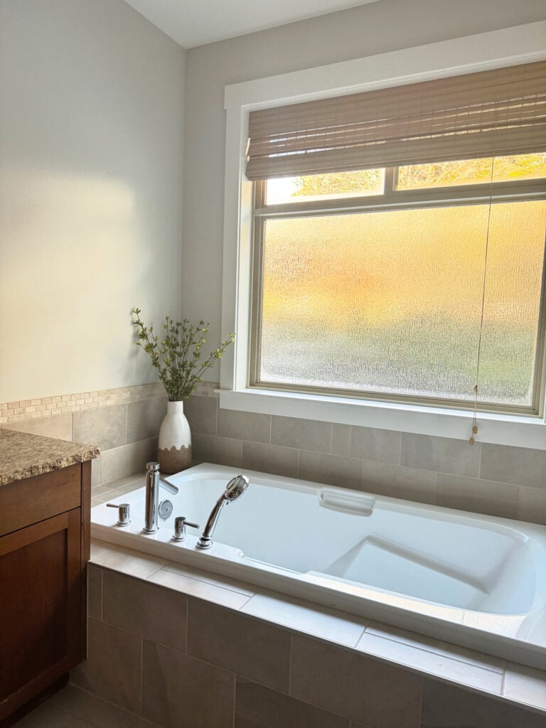 tuscan 2000s style bathroom update, beige pink taupe tile, granite countertop, wood vanity, travertine, soaker tub with tile deck. taupe paint color on walls