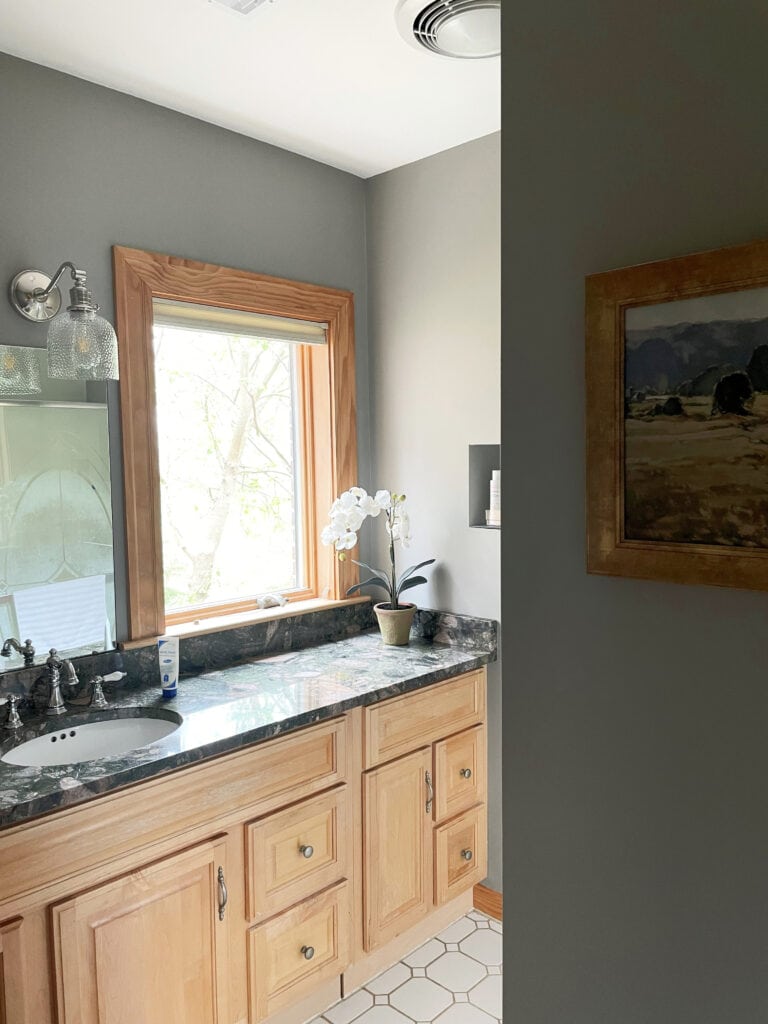 Benjamin Moore Cape May Cobblestone, warm gray greige paint color, granite countertop with rocks and stones in it, maple bathroom cabinet and wood trim