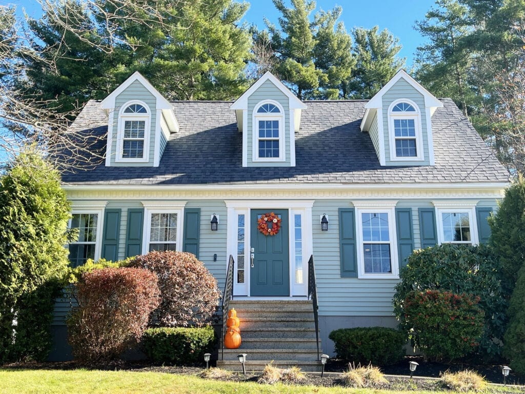Exterior cape cod beachy style home with blue-green-gray siding paint color, Sherwin Oyster BAy, Pure White trim, gray fiberglass roof, Rocky River teal shutters and front door,