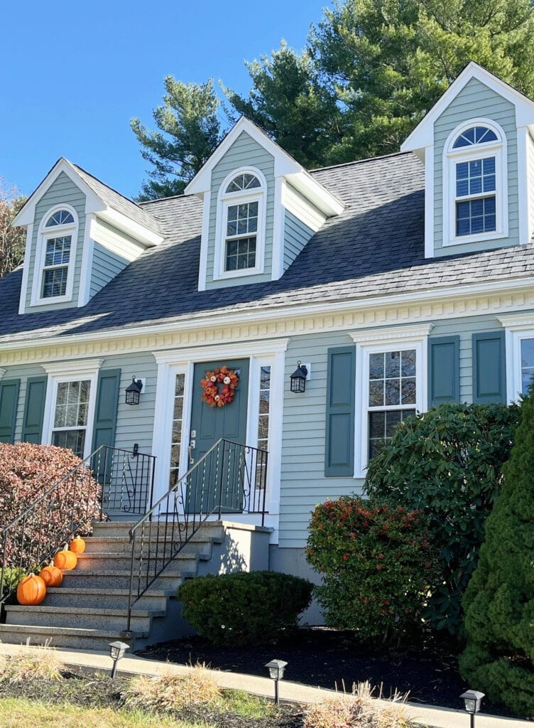 Exterior of cape cod style home with gables, white trim, blue-green-gray siding paint color, Oyster Bay, Rocky River teal front door and shutters, Sherwin Pure White trim (1)