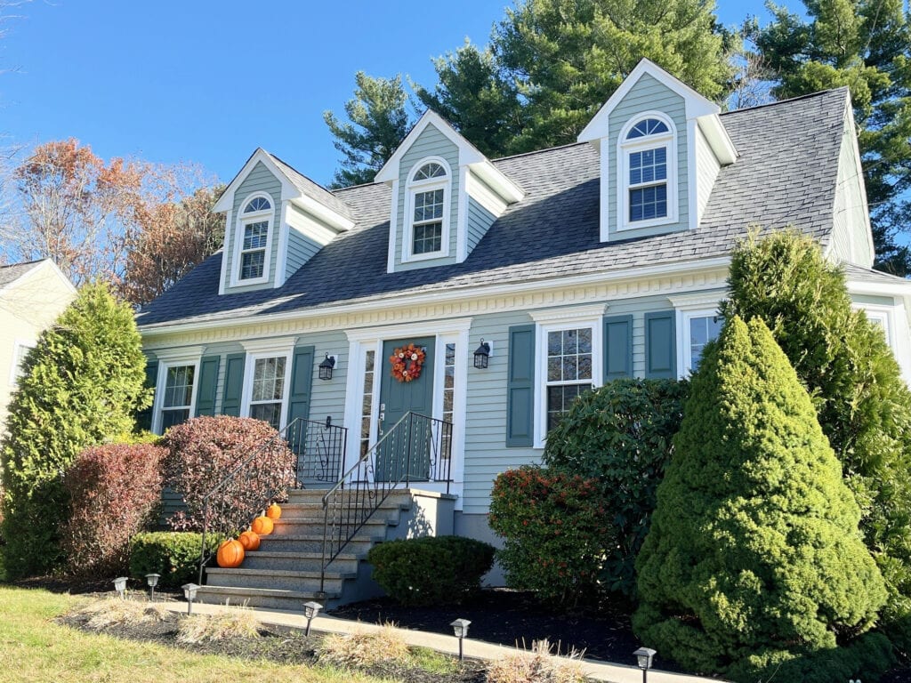 Exterior of cape cod style home with gables, white trim, blue-green-gray siding paint color, Oyster Bay, Rocky River teal front door and shutters, Sherwin Pure White trim