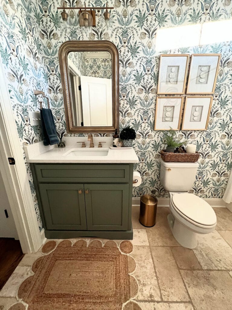 1990 bathroom with travertine tile floor, update ideas with dark green painted vanity, white quartz, floral pattern wallpaper, gold hardware (1)