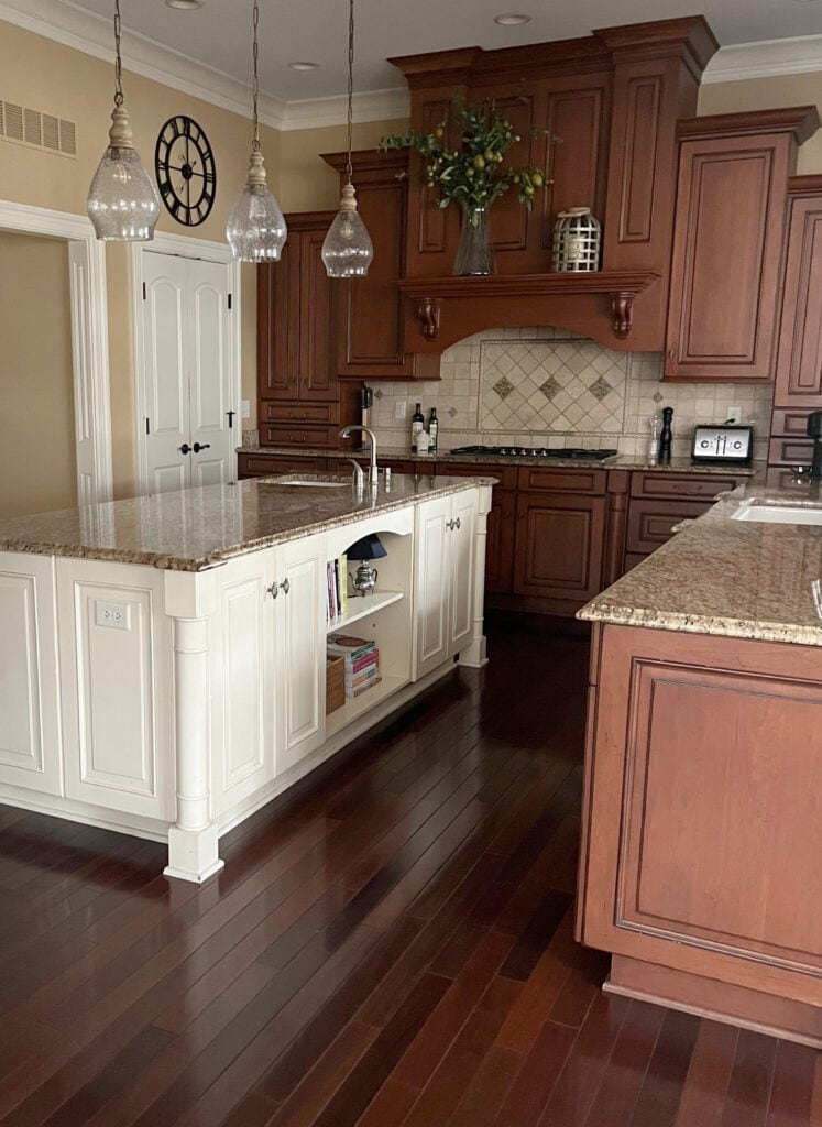 Antique White kitchen island red, cherrry wood cabinets and floor, traavertine tile backsplash, St Cecelia granite countertop, Wilmington Tan Beige on walls. (2)
