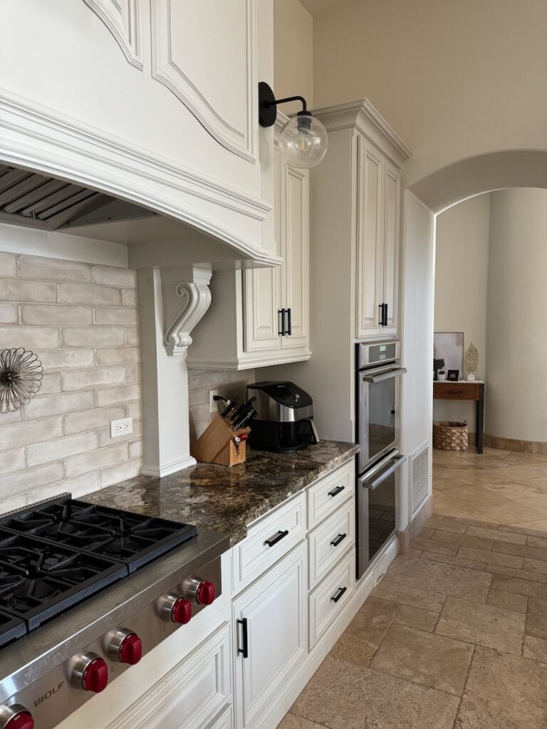 BEFORE Travertine tile floor, Benjamin Moore Dove Wing WALLS, OFF-WHITE PAINT COLOR ON CABINETS, GRANITE COUNTERTOP, TAUPE SUBWAY TILE