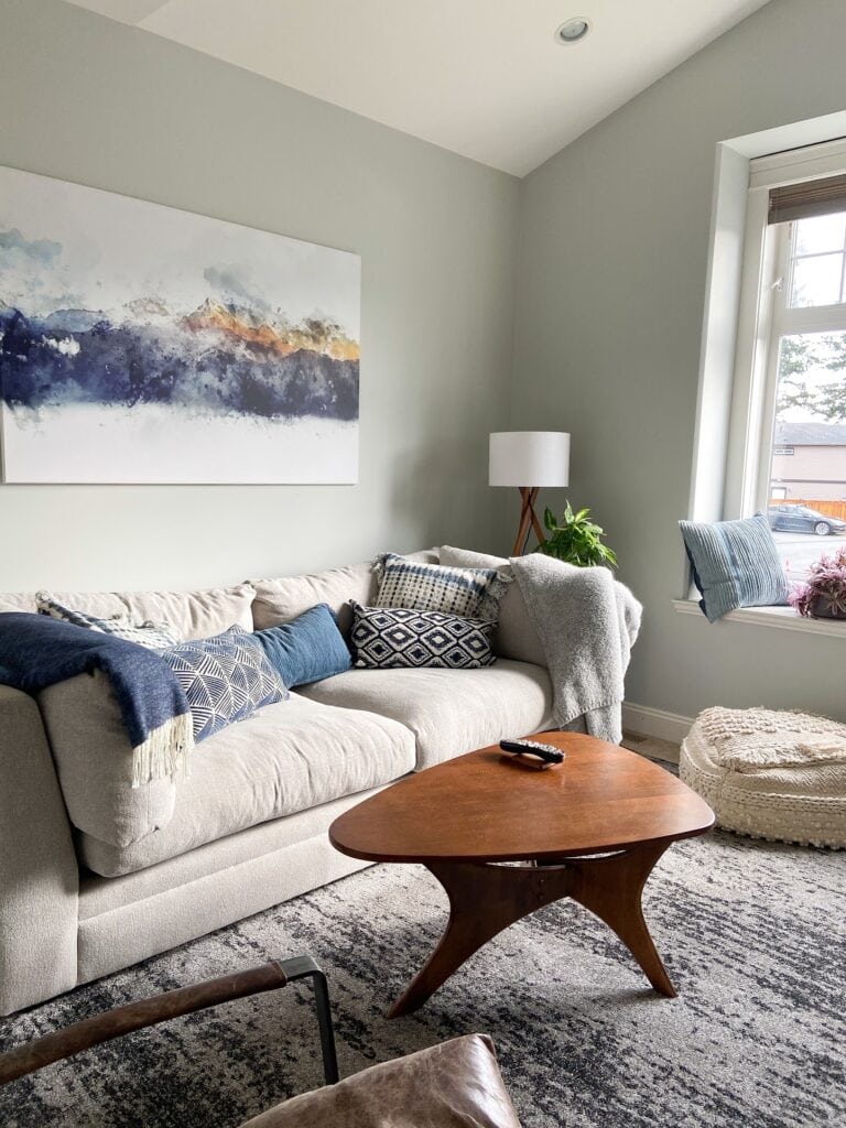 Beige, off-white sofa in den with Benjamin Moore Gray Owl paint color on walls, white trim, blue home decor