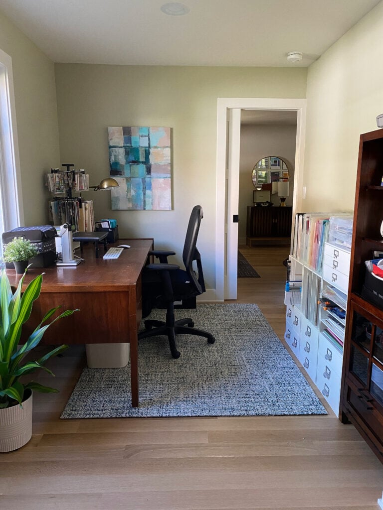 HOme office with white trim and pocket door painted in a green paint color, Sherwin Williams Ancient Marble, pinktoned wood floor.