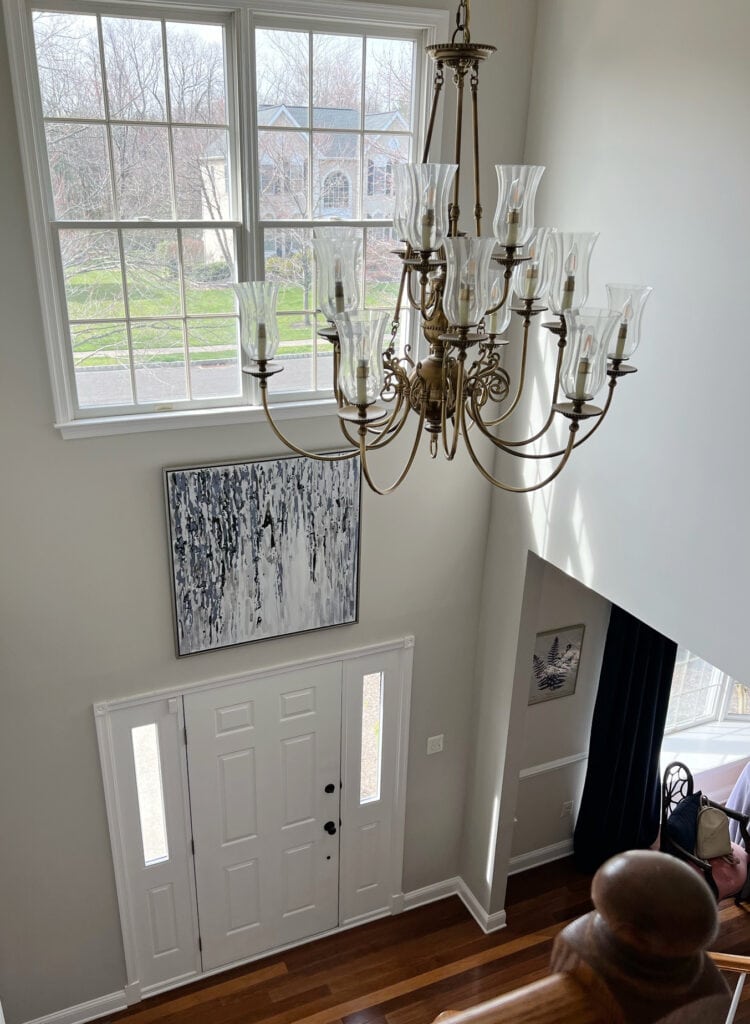 Sherwin Williams AGreeable Gray in two storey foyer with high ceilings and white front door, warm orange toned wood flooring