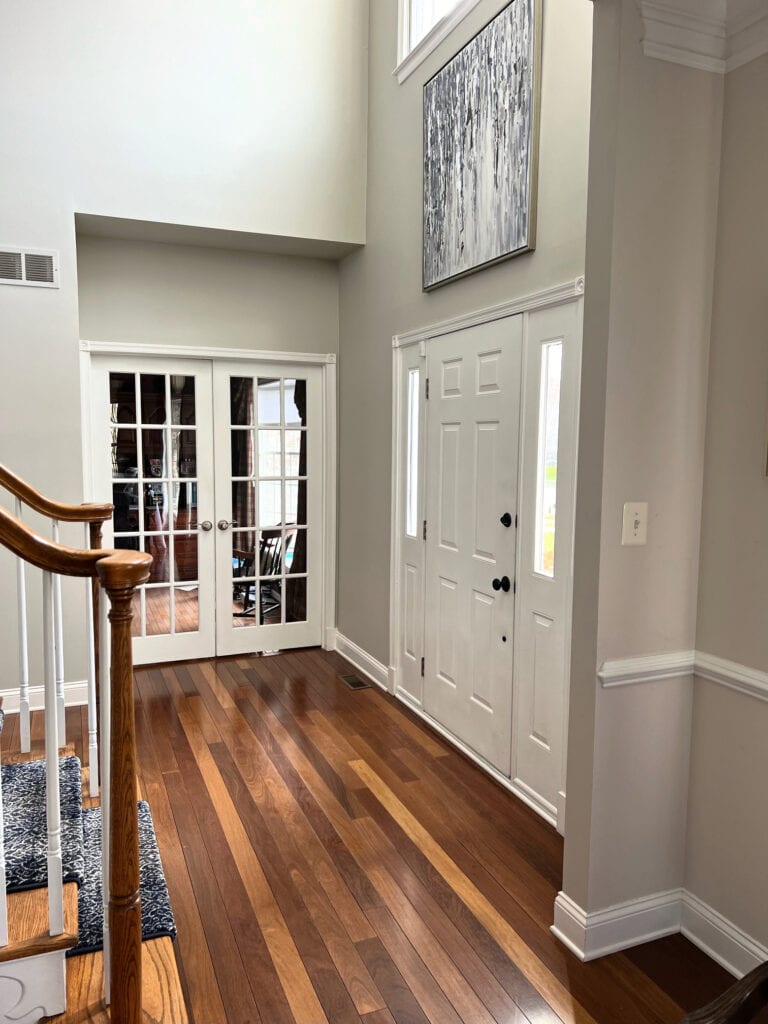 Sherwin Williams Agreeable Gray orange exotic wood flooring red stain, golden oak stair railing, white french doors, white front door.
