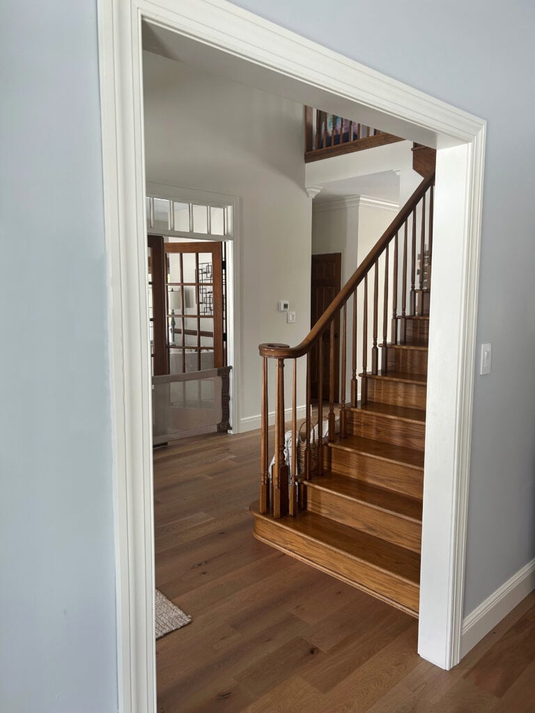 Sherwin Williams NOrth Star blue gray paint color on walls, wood floor, Pearly White trim and color in entryway with wood stairs and hand railing