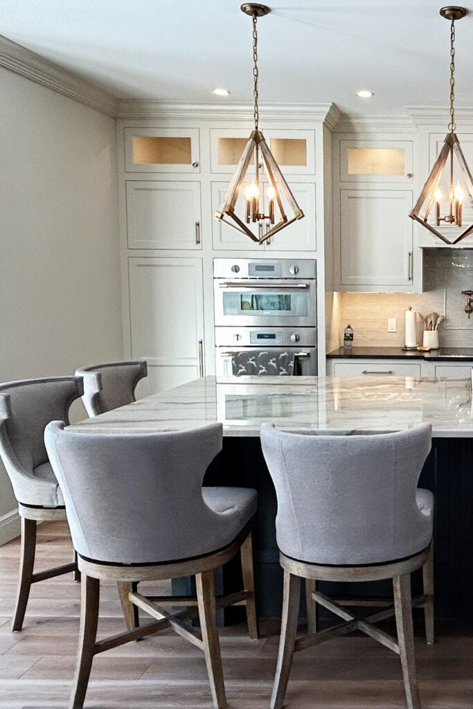 Sherwin Williams Pearly White painted kitchen cabinets, wood floor, quartzite countertop, Benjamin Moore French Beret, dark blue island