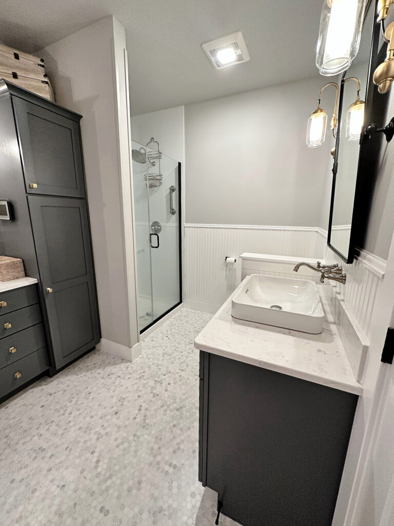 Bathroom walls painted Sherwin Williams On the Rocks gray, Benjamin Moore Chantilly Lace beadboard, Charcoal Slate painted cabinets, wood vanity, white quartz, small marble hexagon tile floor