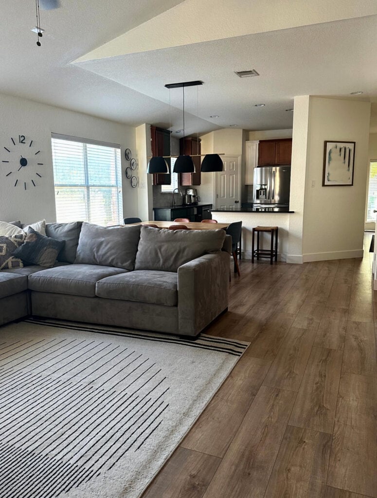 Benjamin Moore Simply White, warm white paint color, looks more yellow on the right, neutral left, wood floor, dark gray sectional