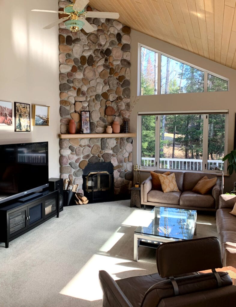 Benjamin Moore Smokey Taupe, Inukshuk, living room with vaulted ceiling, wood ash, river rock stone fireplace, brown leather furniture, carpet