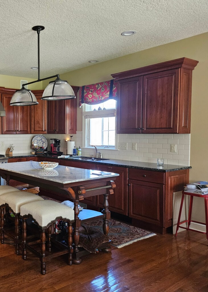 Benjamin Moore Wheeling Neutral iln kitchen, white subway tile, cherry red wood cabinets, oak floor, marble island countertop, stainless steel.