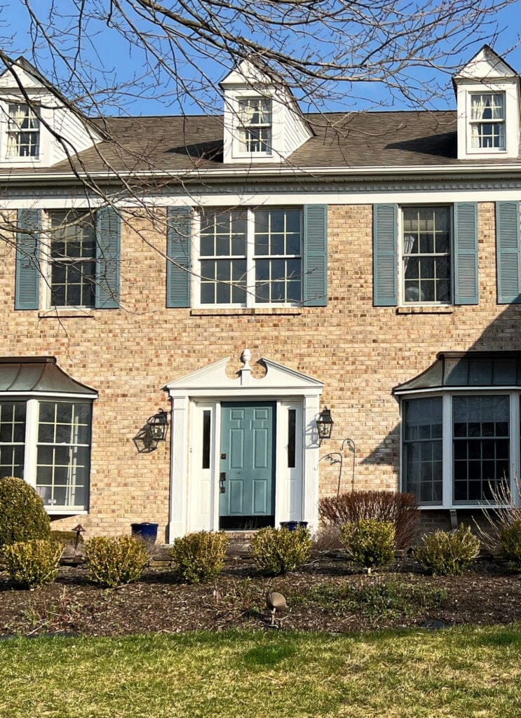Benjamin Moore blue front door and shutters on colonial style, period home with pink, peach, brown, beige coloured brick, warm white trim - Copy