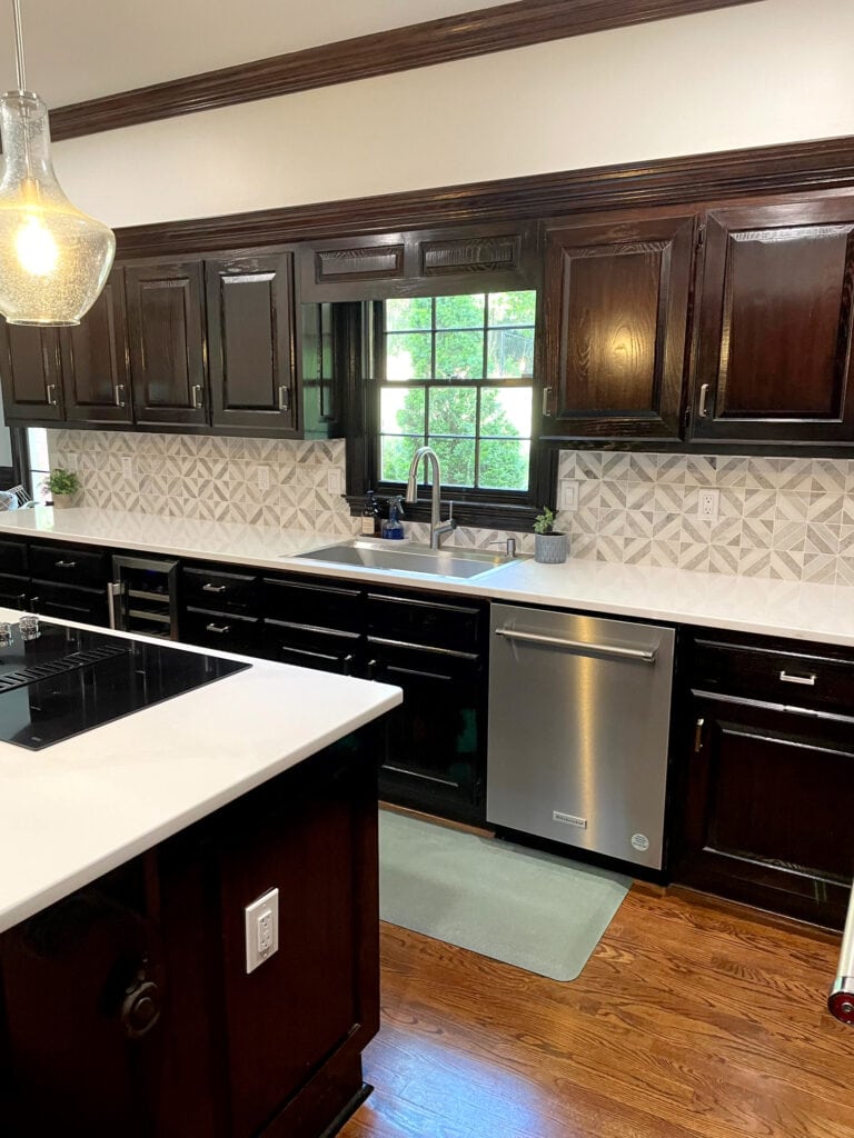 Dark stained wood cabinets, glossy, oak floor, white quartz countertop, backsplash tile, dark wood crown molding