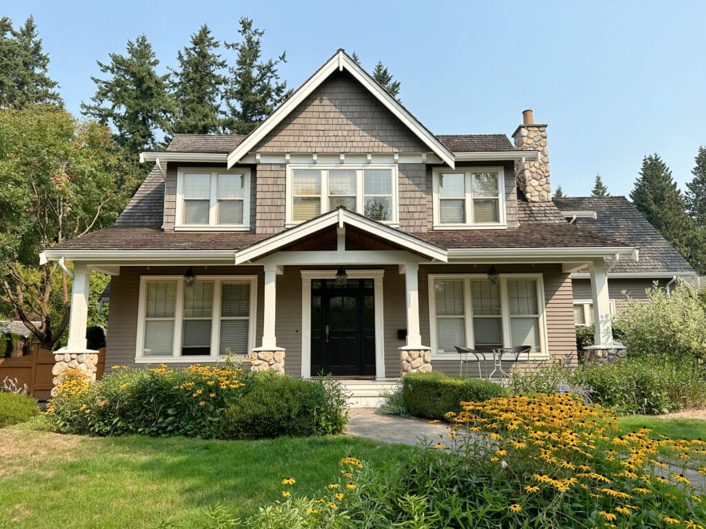 Exterior painted medium neutral paint color, warm white trim, beige tan, almond windows, black front door, cedar shake roof