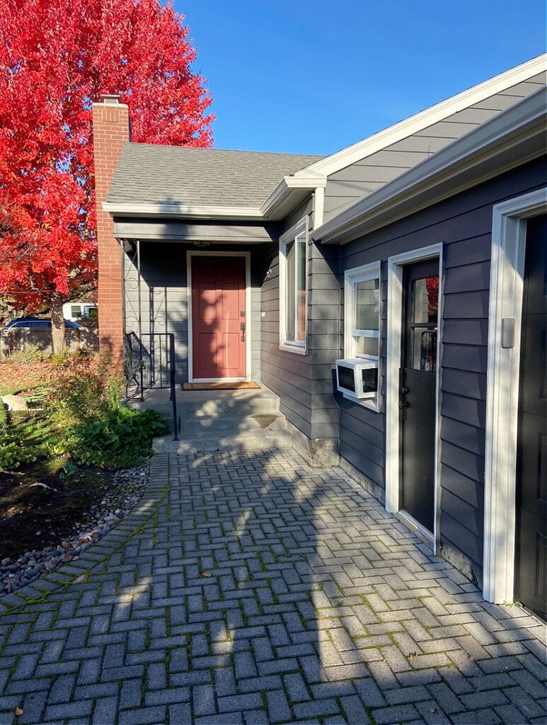 Exterior, red brick chimney, siding painted Sherwin Williams Peppercorn, doors, Tricorn Black, Alabaster trim, red front door