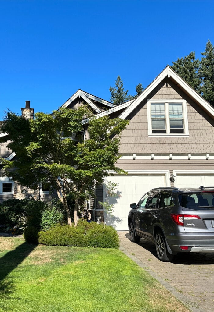 Exterior siding painted medium toned warm gray greige taupe with warm white trim and almond beige windows, garage door