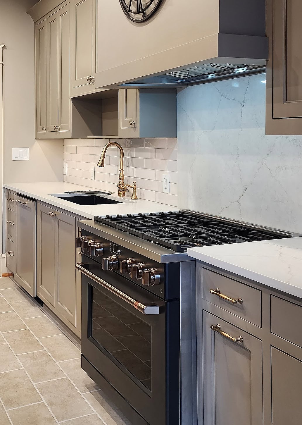 Sherwin Williams Warm Stone lightened on cabinets with zellige look subway tile backsplash, white quartz, Ge Cafe matte black range