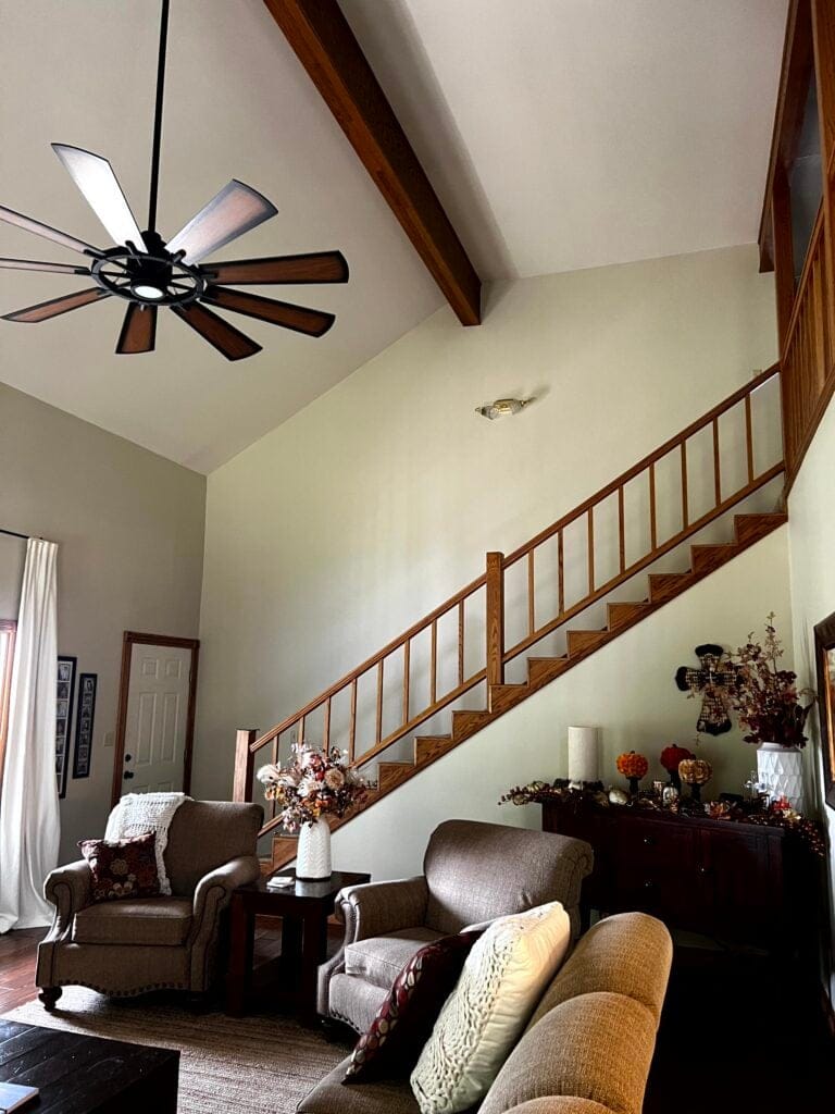 Living room with staircase, wood hand railing, oak, wood trim, vaulted ceiling Sherwin Williams Wool Skein tan paint color on walls, rustic home decor.