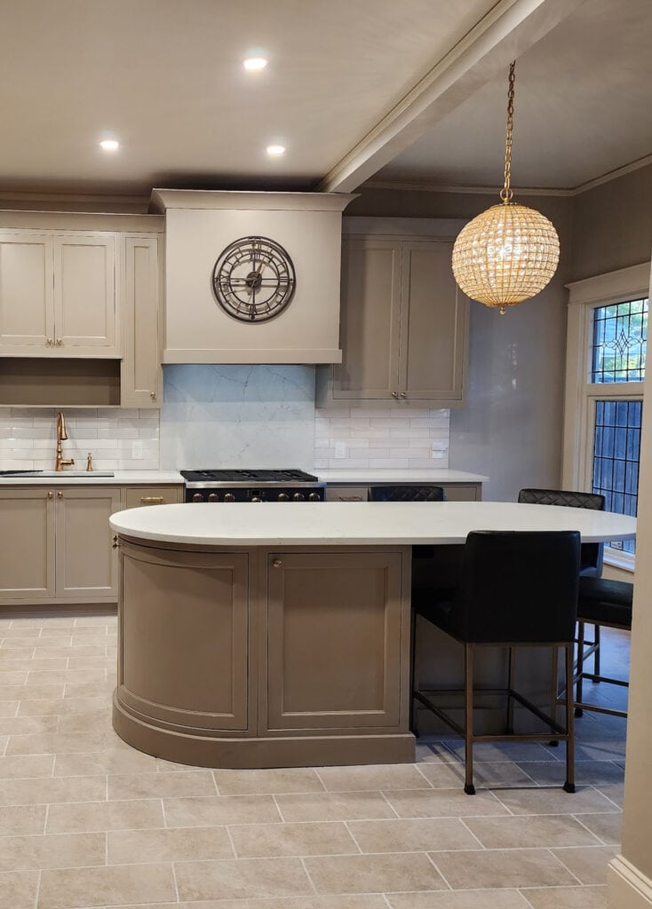 Round or oval island with mushroom taupe, greige, painted kitchen cabinets, beige tile floor, Sherwin Williams, Benjamin Moore Stone Hearth on walls, beige trim, off-white quartz countertop