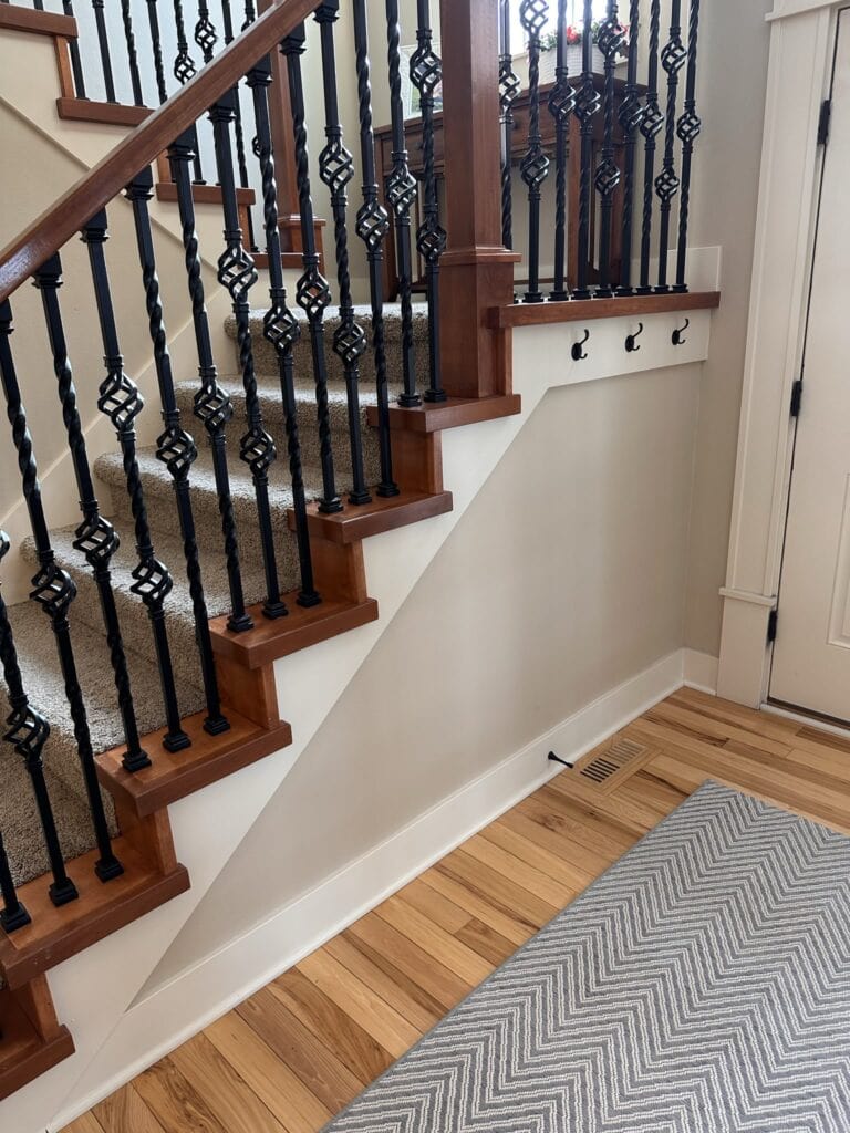 SHERWIN WILLIAMS ANTIQUE WHITE CREAM ON TRIM, MALABAR BEIGE PAINT COLOR ON WALLS, WOOD FLOOR, BEIGE CARPET ON STAIRS, BLACK METAL SPINDLES