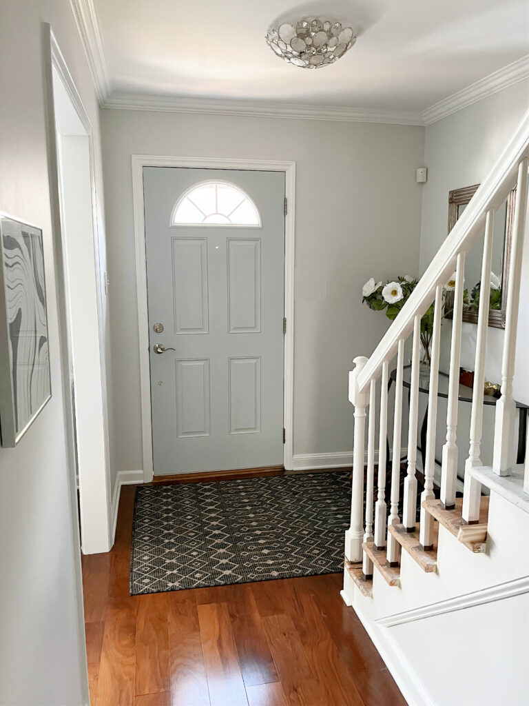 Sherwin Williams Fleur de Sel, off-white gray paint color on walls, Benjamin Moore Super White trim, in entryway foyer with good natural light, Wickham Gray door