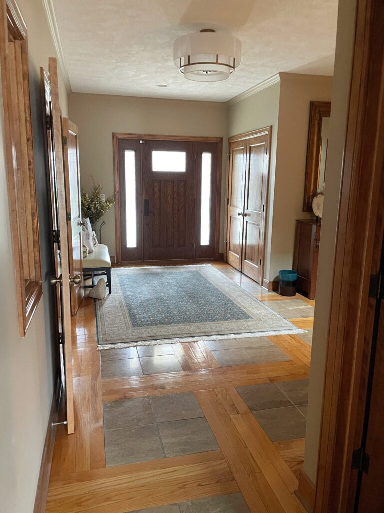 Sherwin Williams Nomadic Desert, beige warm neutral bege color, wood doors, wood trim, tile and wood pattern floor. Entryway.