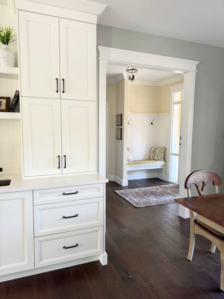 Sherwin Williams Pure White cabinets, Austere Gray paint color on walls with Antique White in entryway, dark wood floor, white quartz countertop
