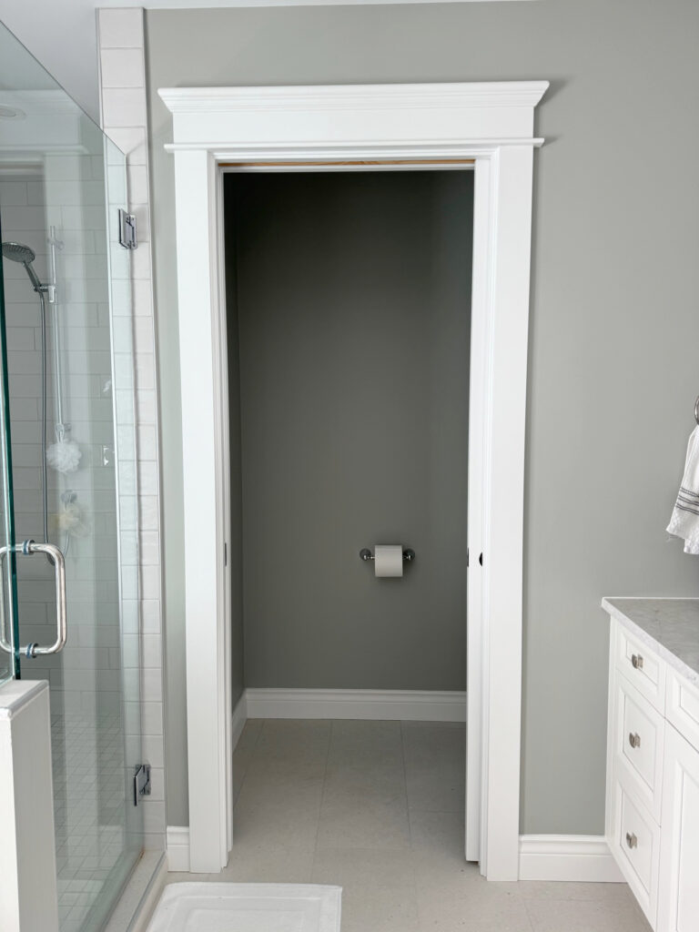 Sherwin Williams Sensible Hue green gray paint color on walls, Pure White trim, Pewter Green on back wall, neutral gray tile floor, white vanity