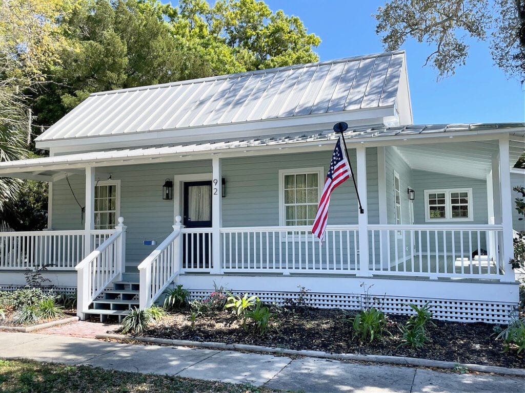 Sherwin Williams Still Water painted front door, light gray silver metal roof, Benjamin Moore White OC 151 trim and Gibraltar front steps and porch floor