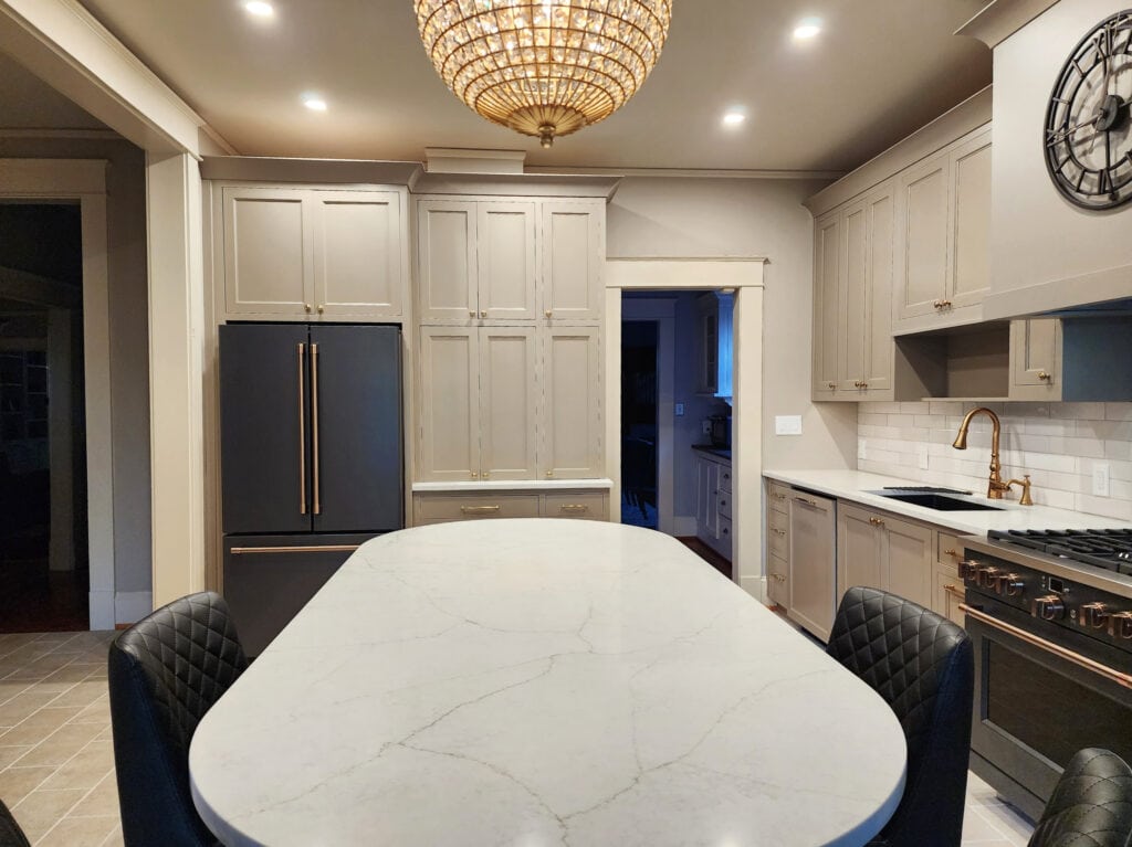 Sherwin Williams mushroom, taupe greige paint color on cabinets, GE Cafe Matte black, brushed bronze hardware, Cambria Ridgegate white quartz, gold hardware, Cream beige trim, Stone Hearth walls