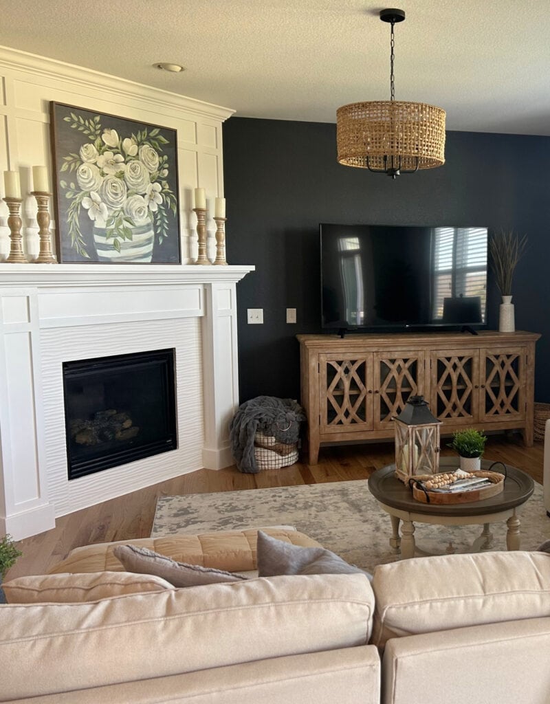 Small family room or living room, angled corner fireplace, white tile, wood mantel surround, dark black blue Benjamin Moore Baby Seal accent wall with TV on cabinet, wood floor