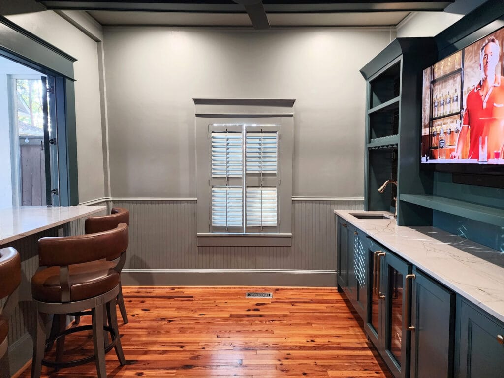 color drench or color wash walls in gray green, beadboard wainscoting, blue-green painted home bar cabinets, quartzite countertops, sitting countertop, stool bar area, wood floor