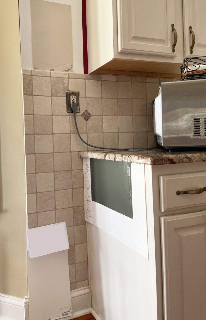 the best paint color to update travertine tile backsplash, cream cabinets, granite countertop, shown here Benjamin Moore Dark Olive, warm soft beige, warm white