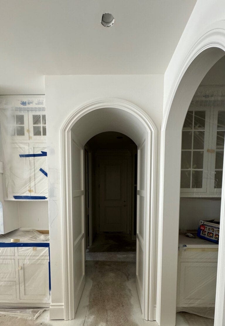 Arched or curved doorway opening to hallway painted in popular warm white paint color, Sherwin Williams Alabaster