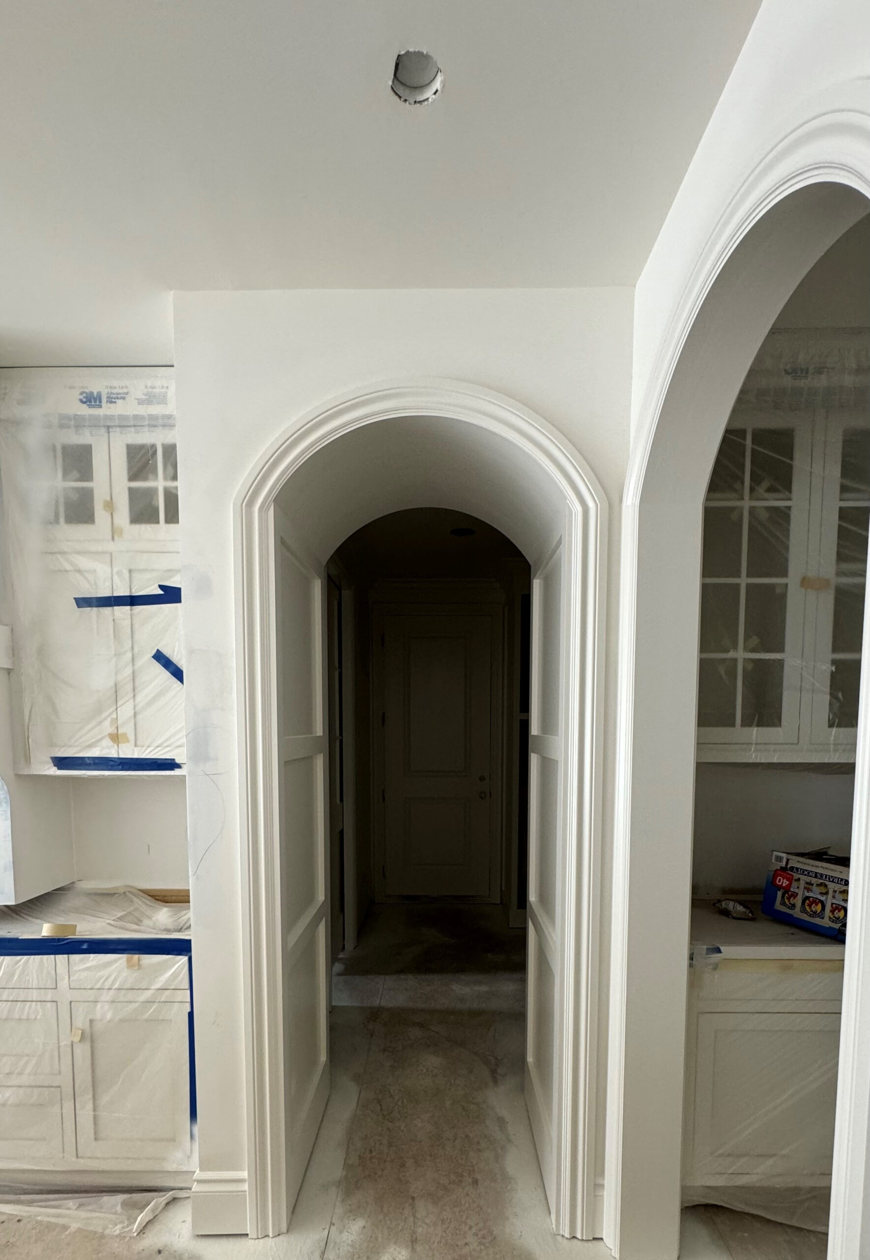 Arched or curved doorway opening to hallway painted in popular warm white paint color, Sherwin Williams Alabaster