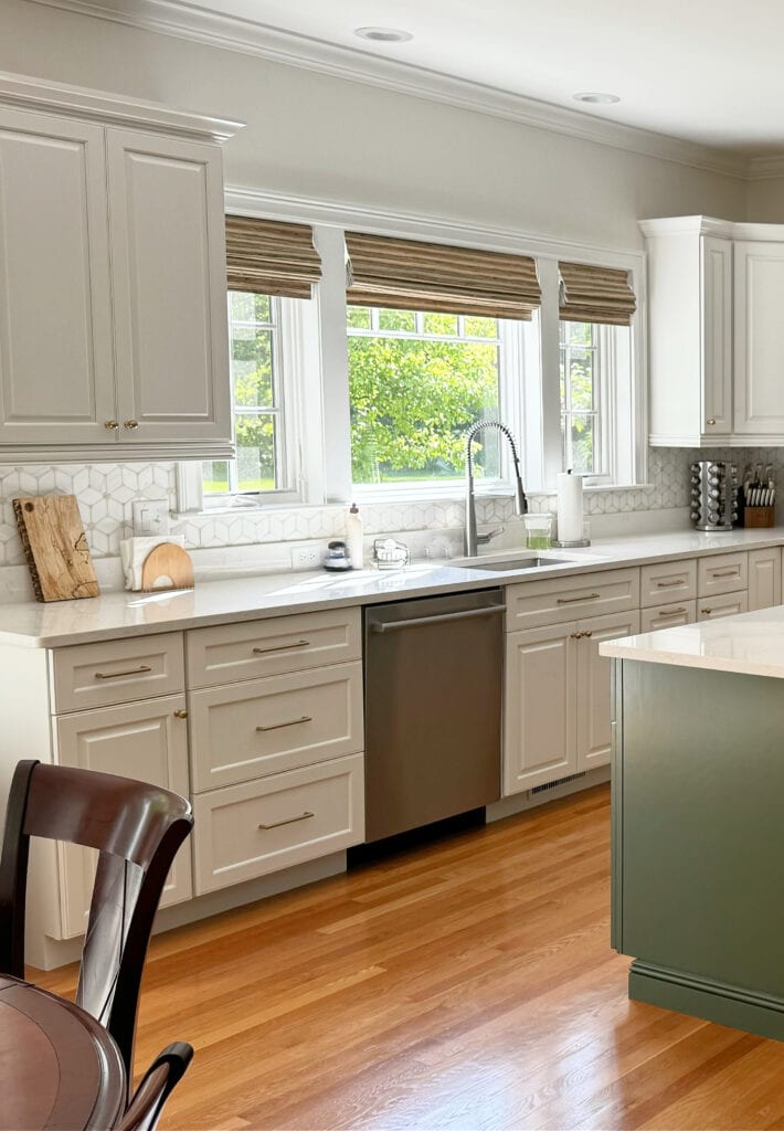 Golden oak floor, green island, soft white quartz countertop, rattan blinds, gold hardware, Sherwin Williams Pearly White off white walls,Kitchen cabinets painted Benjamin Moore White Dove